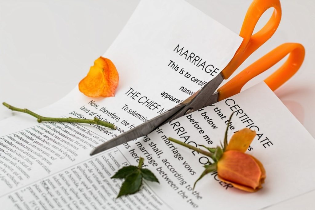 certidão de casamento com uma rosa laranja sendo cortadas por uma tesoura de cabo laranja