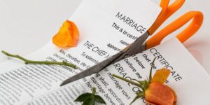 certidão de casamento com uma rosa laranja sendo cortadas por uma tesoura de cabo laranja