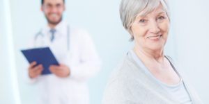 Uma imagem de fundo azul claro, com um médico sorrindo ao fundo e uma senhora sorrindo na frente